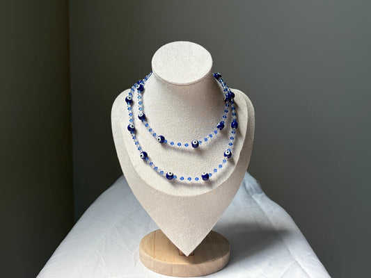 A double-strand Swarovski cryatl beaded necklace with dark blue and light blue beads, displayed on a cream-colored jewelry bust against a dark gray background.