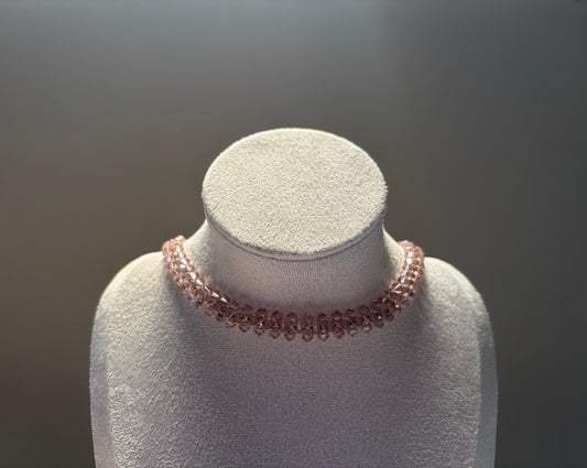 A delicate rose gold Swarovski crystal beaded solid choker necklace displayed on a textured white jewelry bust against a dark gray gradient background.