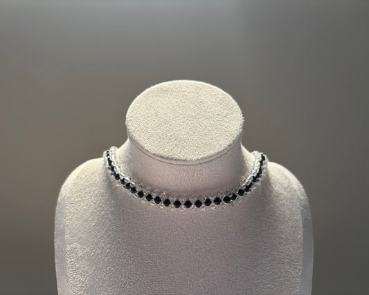A delicate black Swarovski crystal beaded striped choker necklace with clear faceted beads, displayed on a white textured jewelry bust against a neutral gray background.